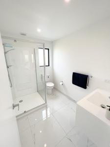 ein weißes Badezimmer mit Dusche und Toilette in der Unterkunft Coastal Charm Escape in Karikari Peninsula