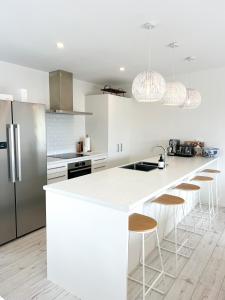 eine Küche mit weißen Arbeitsplatten und Küchengeräten aus Edelstahl in der Unterkunft Coastal Charm Escape in Karikari Peninsula