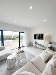 ein weißes Wohnzimmer mit einer Couch und einem Tisch in der Unterkunft Coastal Charm Escape in Karikari Peninsula + 19 Fotos