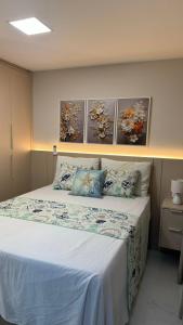 a bedroom with a bed with three paintings on the wall at MW Apto em BV - Requinte e conforto em um so lugar in Recife