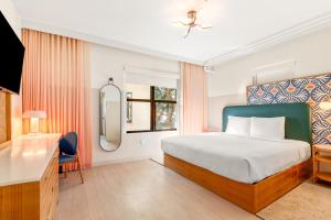 Un dormitorio con una cama, un escritorio y un espejo. en Beach Plaza, en Miami Beach