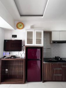 Il comprend une cuisine équipée d'un réfrigérateur rouge et d'une horloge murale. dans l'établissement Raja Apartemen Jarrdin Type 33, à Bandung