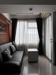 un salon avec un canapé et une grande fenêtre dans l'établissement Raja Apartemen Jarrdin Type 33, à Bandung