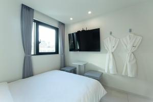 a white bedroom with a bed and a tv at Aank Air Hotel Gaebong in Seoul +40 photos