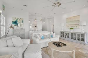 a white living room with two white couches and a table at Emerald View on 30A in Santa Rosa Beach