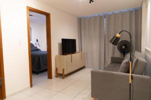 a living room with a tv and a chair with a lamp at Paraíso em Tambauzinho in João Pessoa