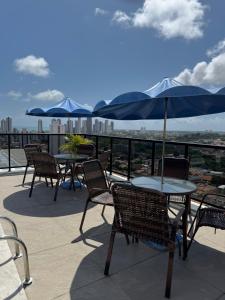 a patio with tables and chairs with blue umbrellas at Paraíso em Tambauzinho in João Pessoa