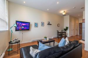 a living room with a couch and a tv on a wall at Sunny Downtown Loft with AC, Unit #2 in Halifax
