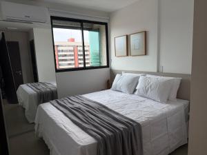 a white bedroom with two beds and a window at Ponta Verde Paradise Liv Residence 500m da Praia in Maceió +35 photos