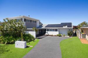 una casa con un tetto solare su un cortile verde di Deja Bleu - great family home with jetty a Port Macquarie