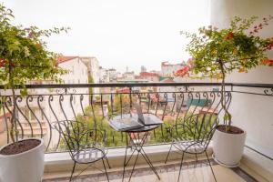 un balcone con 2 piante in vaso e un tavolo di Hotel Du Palace a Hanoi
