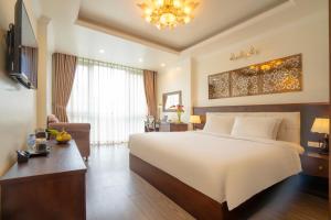 una camera da letto con un grande letto bianco e una scrivania di Hotel Du Palace a Hanoi