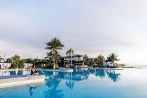 een vrouw die op de rand van een zwembad zit bij Serenity Cottage Beach Escape in Yeppoon