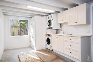 een keuken met witte kasten en een wasmachine en droger bij Serenity Cottage Beach Escape in Yeppoon