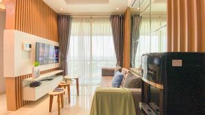 eine Person, die auf einer Couch in einem Wohnzimmer sitzt in der Unterkunft Fancy and Nice 1BR at Citralake Suites Apartment By Travelio in Jakarta