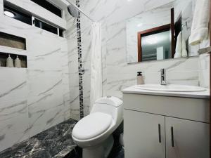 a white bathroom with a toilet and a sink at Andes Retreat 5 Bedroom 3 Bath in Baños
