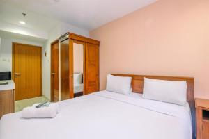 a bedroom with a white bed with a wooden headboard at Classic and Cozy Studio at Cinere Bellevue Suites Apartment By Travelio in Depok +11 photos