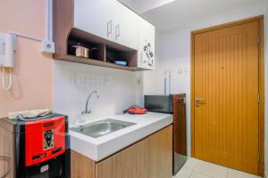 a small kitchen with a sink and a red microwave at Classic and Cozy Studio at Cinere Bellevue Suites Apartment By Travelio in Depok