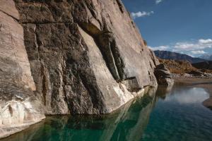 a large rock wall next to a body of water at Khan Guest House in Engilʼchek