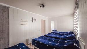 a room with four beds with blue sheets on them at Khan Guest House in Engilʼchek