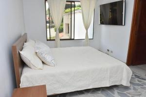 une chambre avec un lit avec des draps blancs et une fenêtre dans l'établissement spectacular Casa Ashley, à Cali