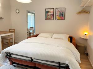 Un dormitorio con una cama grande con sábanas blancas. en Confortable studio 15 min Paris, en Saint-Maurice