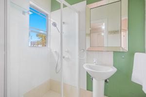 a bathroom with a shower and a sink and a mirror at Sun Catcher - ocean views, walk to beach, lake, cafés, shops in Lake Cathie +15 photos