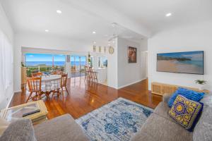 a living room with a couch and a table and a dining room at Sun Catcher - ocean views, walk to beach, lake, cafés, shops in Lake Cathie