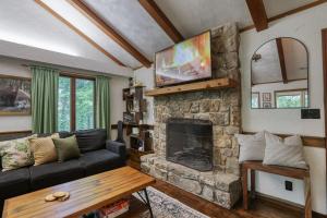 a living room with a couch and a stone fireplace at Treetop Hideaway - Summer Escape with HOT TUB in Gatlinburg