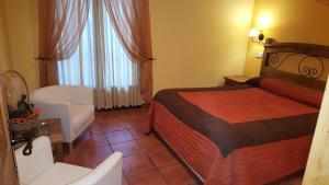 Habitación de hotel con cama, silla y ventana en Madre Terra, en La Puebla de la Sierra