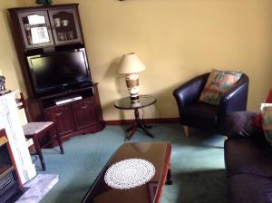 a living room with a tv and a chair and a table at Riverlodge Self Catering in Kenmare