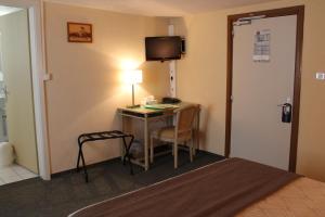 een hotelkamer met een bureau met een lamp en een bed bij Auberge des Trois Châteaux in Eguisheim