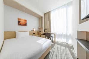 a hotel room with a bed and a desk at JR Kyushu Hotel Blossom Shinjuku in Tokyo
