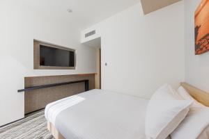 a bedroom with a bed and a tv on the wall at JR Kyushu Hotel Blossom Shinjuku in Tokyo