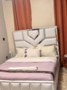 a white bed with a white headboard and pillows at Fatisa homes in Kampala