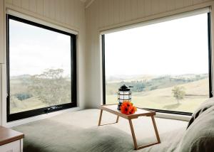 Un dormitorio con grandes ventanas y una mesa con flores. en Tiny Mowgli, en Bulliac 12 fotos más