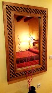 a mirror hanging on a wall with a red cord at Madre Terra in La Puebla de la Sierra