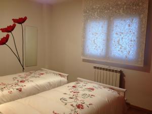 - une chambre avec 2 lits et une fenêtre ornée de fleurs rouges dans l'établissement Apartamento Turistico Cigüeña de Arguedas, à Arguedas