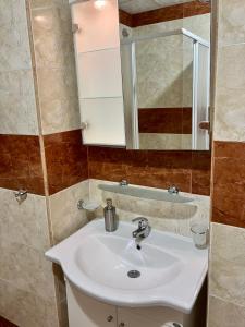 a bathroom with a white sink and a mirror at Sea Coast Apartment - 17 pools included in Sveti Vlas +17 photos