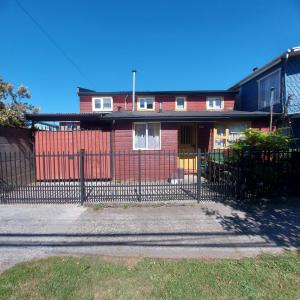 una casa rossa con una recinzione di fronte di Casa Equipada Puerto Varas a Puerto Varas