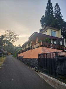 a house with a fence on the side of a street at Villa PakDe Hulu Cai in Ciawi