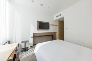 a bedroom with a bed and a tv on the wall at JR Kyushu Hotel Blossom Shinjuku in Tokyo