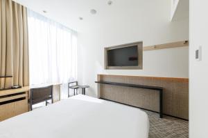 a hotel room with a bed and a tv at JR Kyushu Hotel Blossom Shinjuku in Tokyo