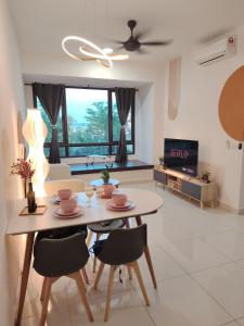 un salon avec une table, des chaises et une télévision dans l'établissement Sunway Greenfield Residence with Amazing Pool Facilities, à Petaling Jaya