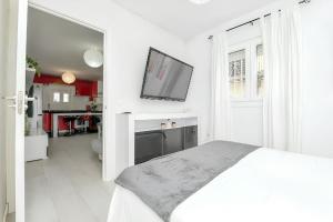 a white bedroom with a bed and a flat screen tv at Charming House in Chiclana de la Frontera with Terrace in Chiclana de la Frontera