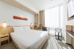 a hotel room with a white bed and a desk at JR Kyushu Hotel Blossom Shinjuku in Tokyo