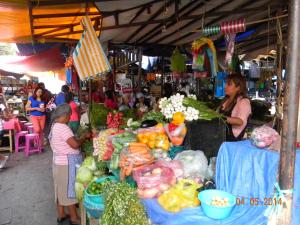 a little girl standing next to a market with fruits and vegetables at Tubohotel in Tepoztlán