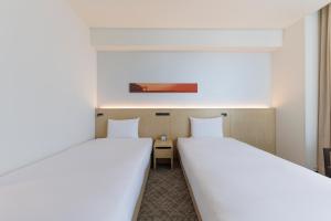 two twin beds in a room with at JR Kyushu Hotel Blossom Shinjuku in Tokyo