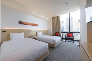 a hotel room with two beds and a desk at JR Kyushu Hotel Blossom Shinjuku in Tokyo