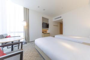 a hotel room with two beds and a table at JR Kyushu Hotel Blossom Shinjuku in Tokyo